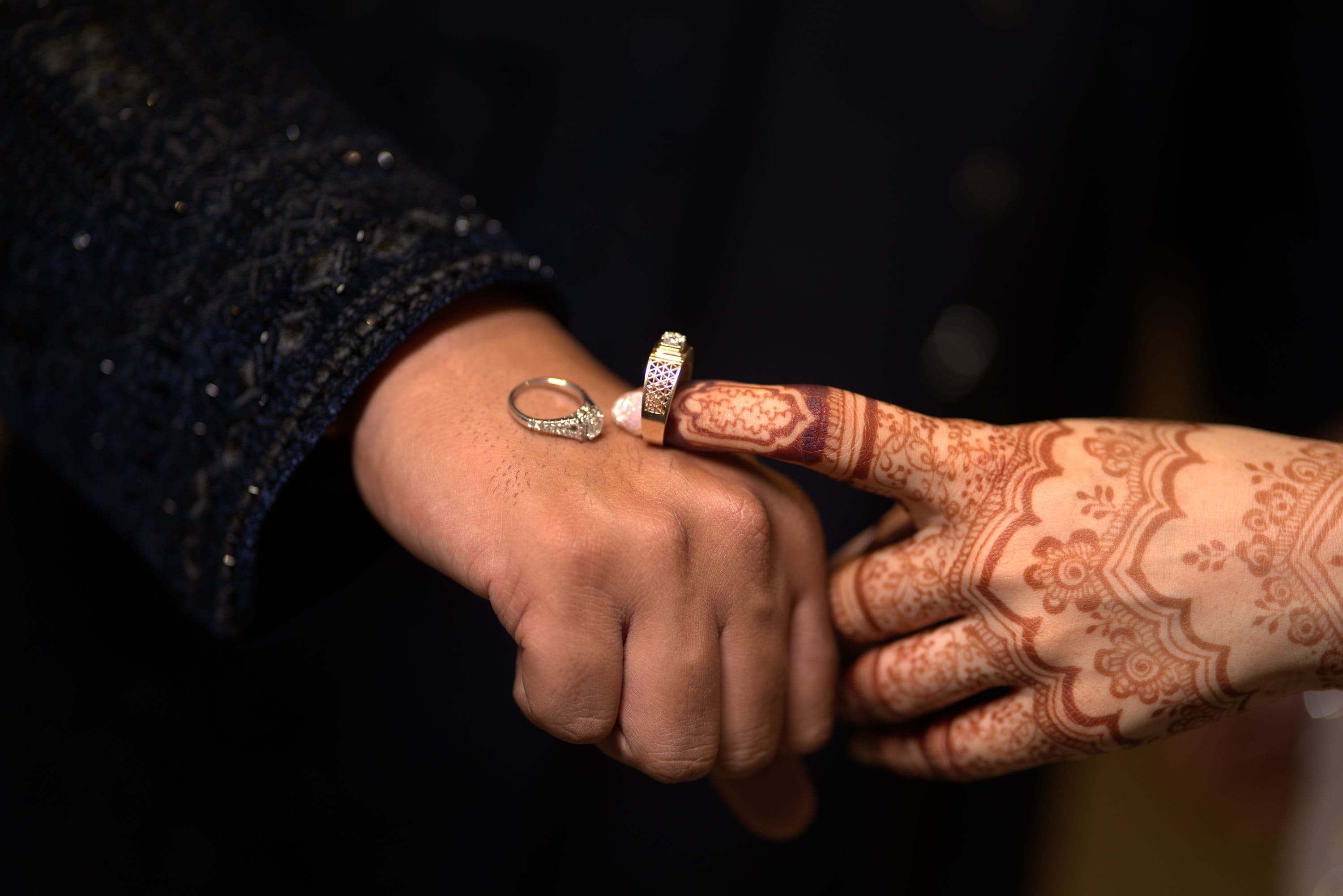 Their hands together, mehndi and the ring, close up