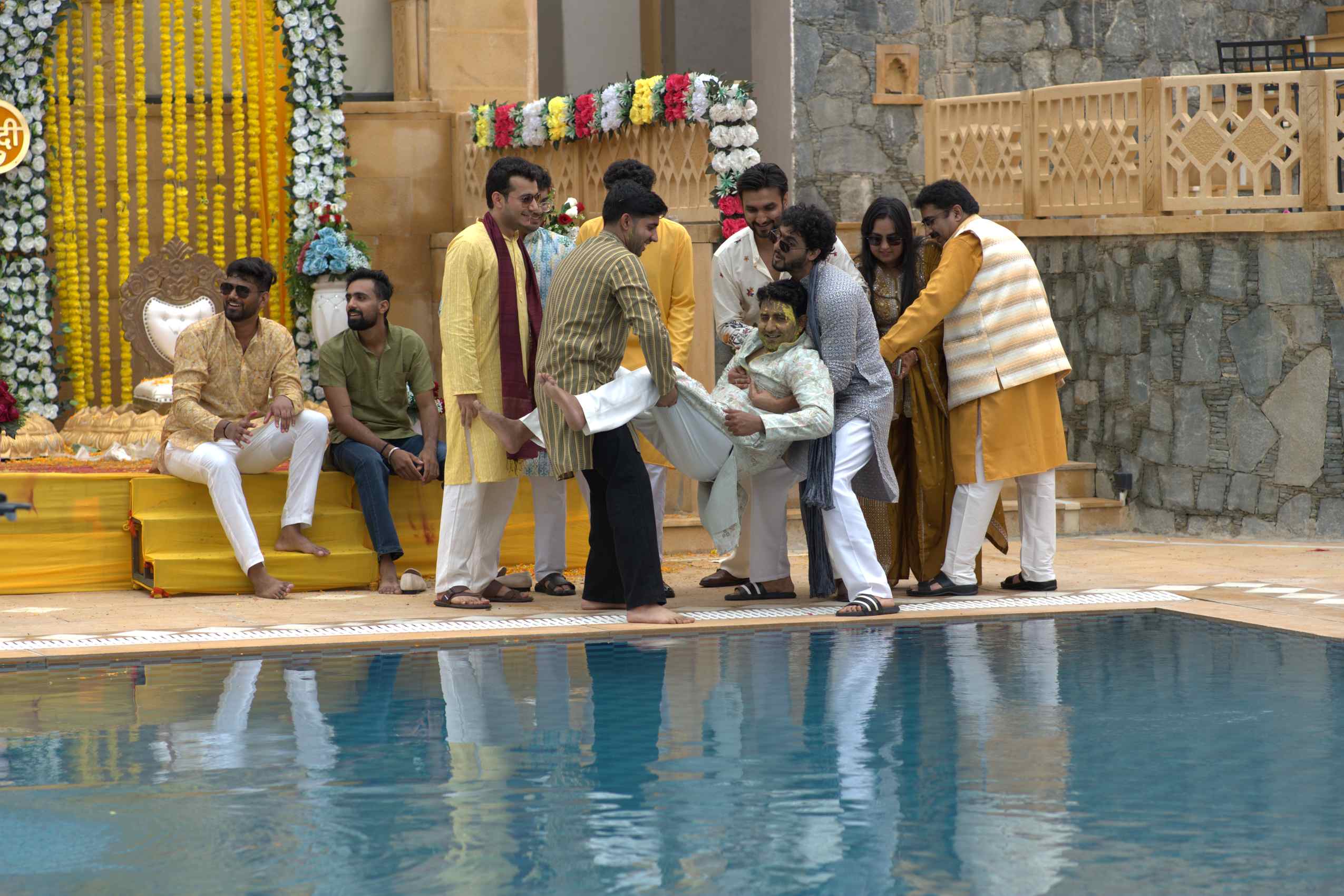 Friends carrying the groom towards the pool
