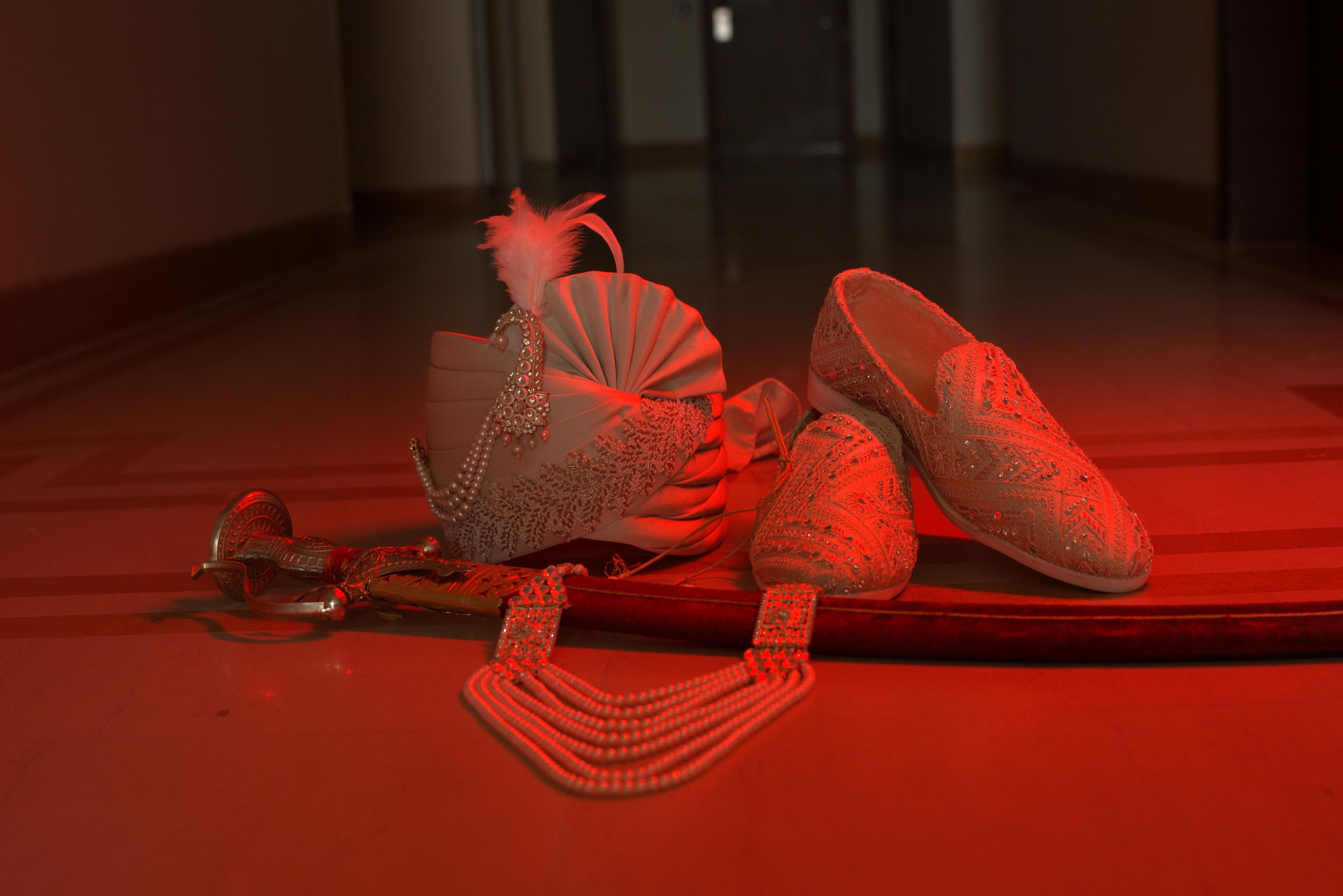 The turban, shoes and sword laid out under red light